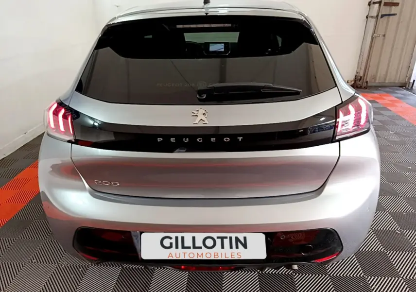 Vue arrière d'une Peugeot 208 gris clair avec feux LED caractéristiques allumés dans un garage.