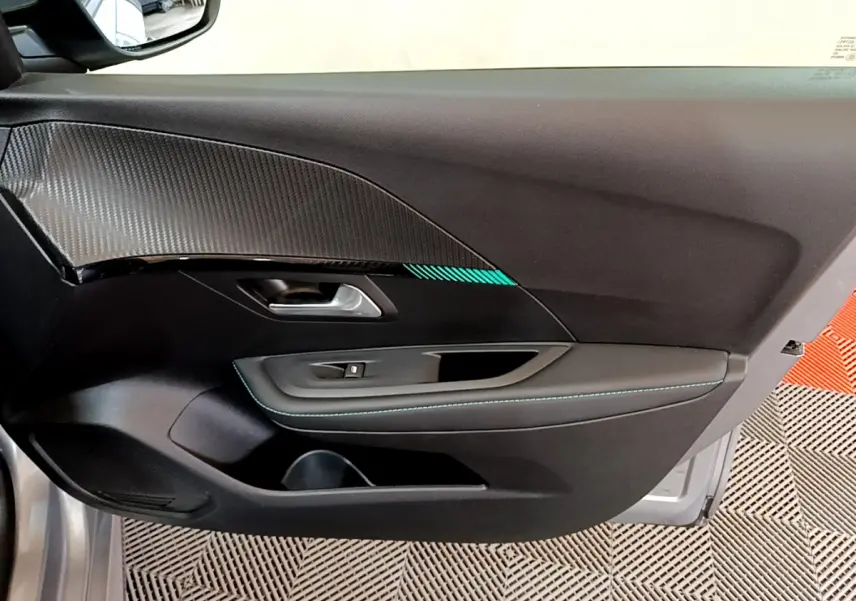Vue rapprochée de la porte avant gauche gris clair de la Peugeot 208 avec insert décoratif et surpiqûres bleues.