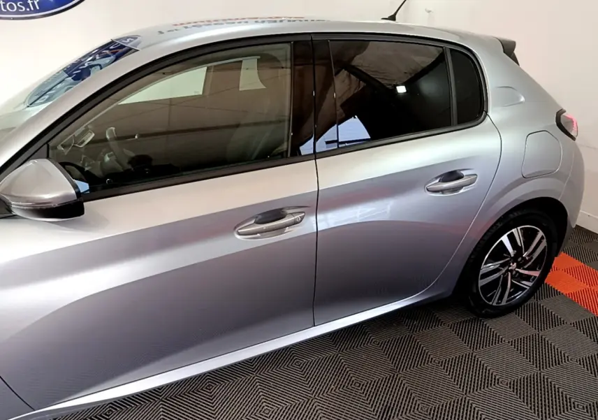 Profil côté gauche d'une Peugeot 208 gris clair 2020 avec jantes alliage et vitres teintées.