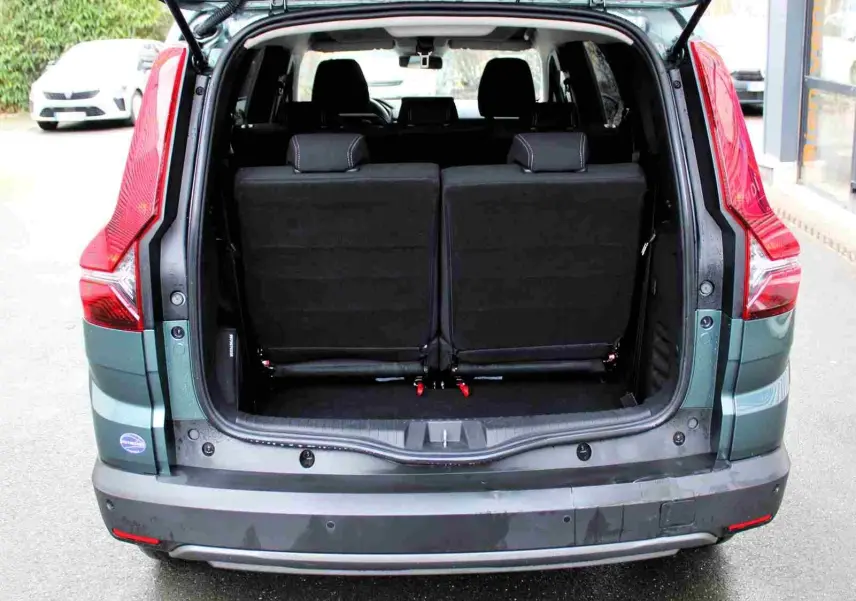 Vue arrière du Dacia Jogger 2025 vert cèdre métal avec coffre ouvert et sièges rabattus visibles.