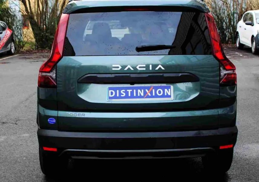Vue arrière d'une Dacia Jogger vert cèdre métal 2025 avec logo DACIA et plaque Distinxion visible.
