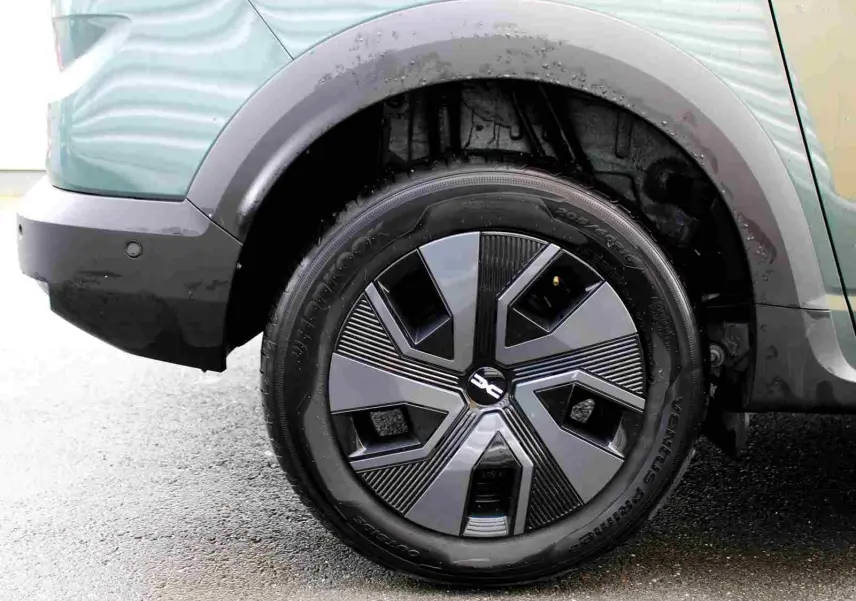 Gros plan sur la roue arrière gauche du Dacia Jogger vert cèdre métal, mettant en valeur la jante au design moderne.