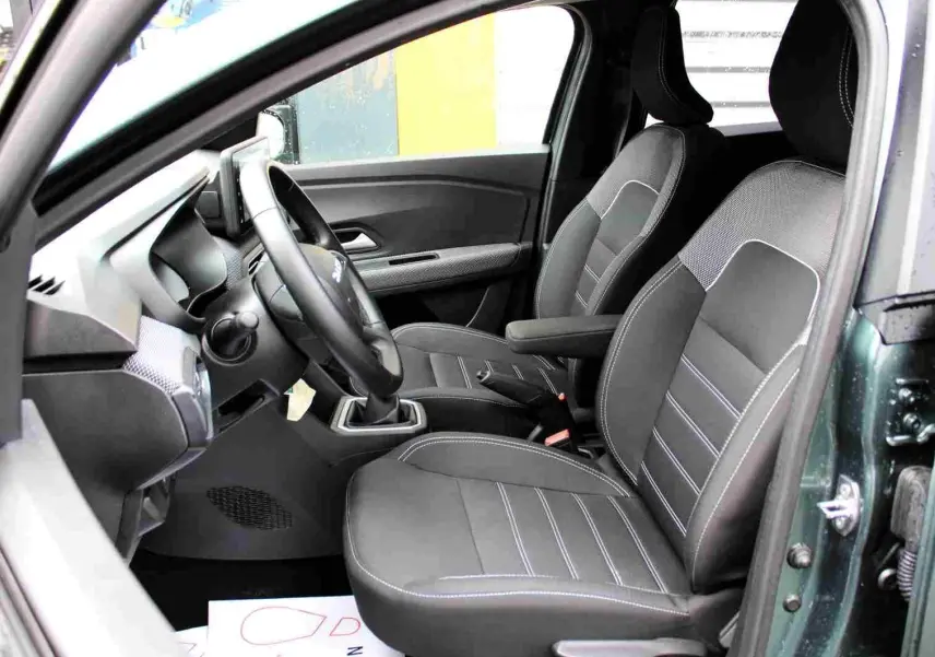 Vue intérieure côté conducteur du Dacia Jogger 2025 vert cèdre, montrant les sièges noirs et le volant multifonction.