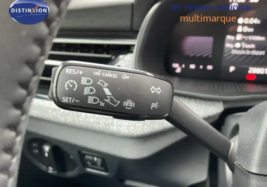 Gros plan sur la commande de régulateur de vitesse du Skoda Kamiq 2025, intérieur gris graphite avec tableau de bord numérique flou.