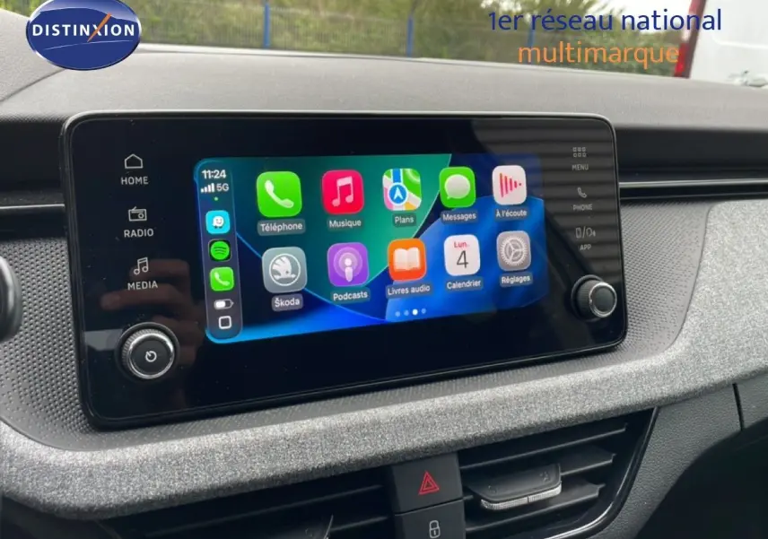 Écran tactile central du Skoda Kamiq 2025 affichant l’interface Apple CarPlay, avec tableau de bord gris texturé en arrière-plan.