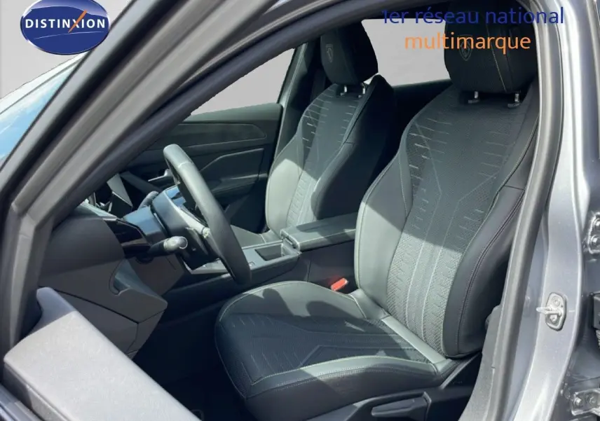 Vue intérieure côté conducteur d'une Peugeot 308 gris Artense, mettant en valeur les sièges noirs en tissu et cuir.