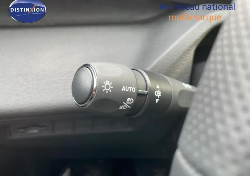 Gros plan sur la commande des phares automatique à gauche du volant dans l’habitacle d’une Peugeot 308 gris Artense.