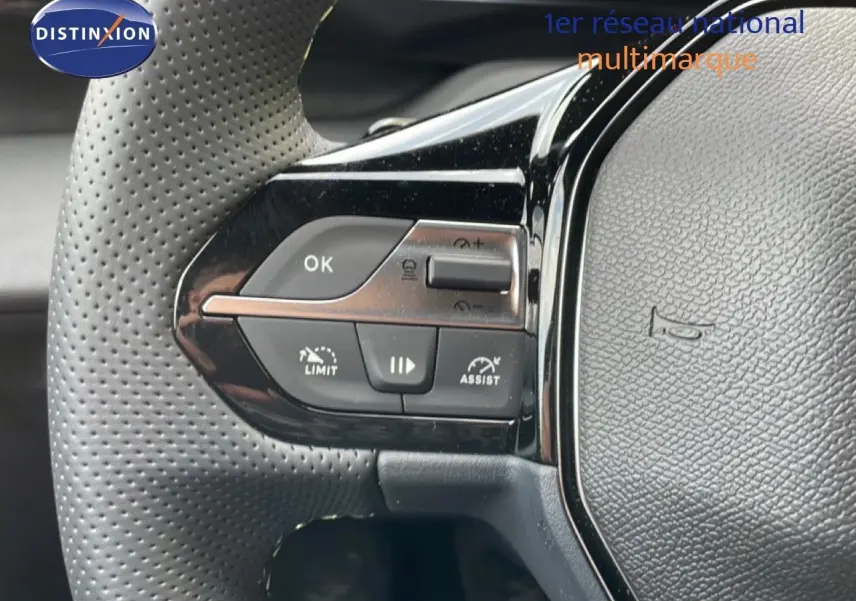Gros plan sur le volant perforé côté gauche de la Peugeot 308 gris Artense, avec commandes intégrées et finition brillante.