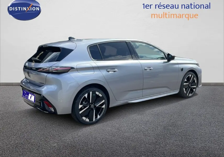 Peugeot 308 1.2 Hybrid 145ch gris Artense métal vue 3/4 arrière droit avec jantes noires et détails modernes.