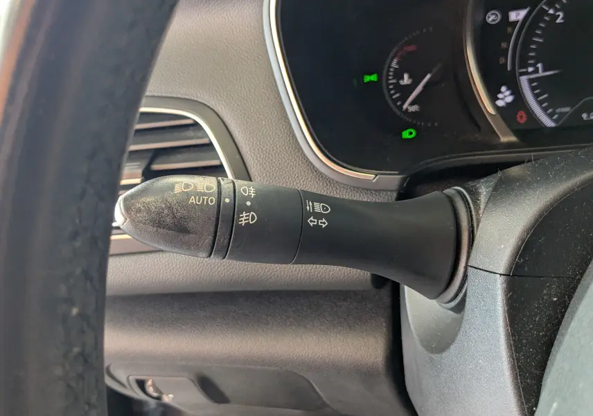 Gros plan sur la manette de clignotants et phares à gauche du volant d’une Renault Mégane IV gris 2019.