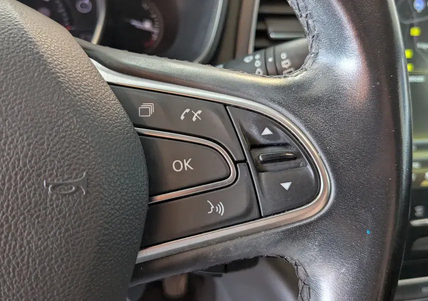 Gros plan sur les boutons de commande à droite du volant noir d’une Renault Mégane IV gris 2019, version Intens.