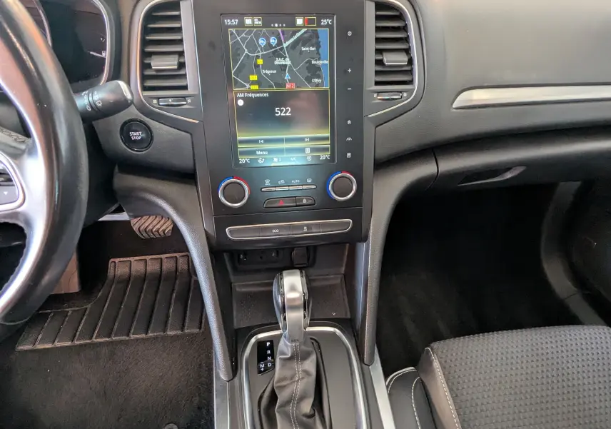Vue intérieure centrée sur la console centrale d'une Renault Mégane IV grise avec écran tactile et levier de boîte automatique.
