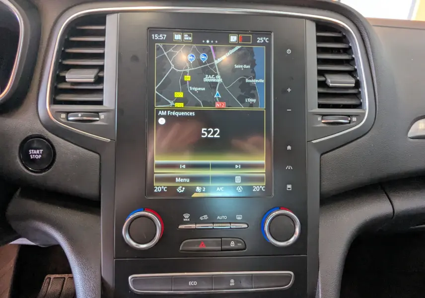 Vue rapprochée du tableau de bord de la Renault Mégane IV gris, avec écran tactile affichant la navigation et la radio.