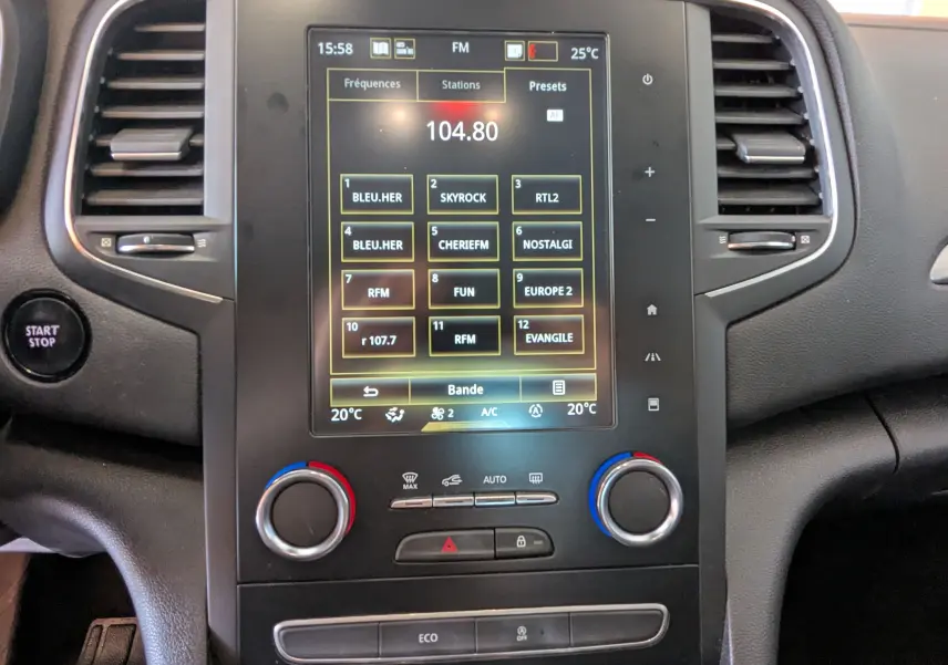 Vue rapprochée de la console centrale de la Renault Mégane IV gris, avec écran tactile radio et commandes de climatisation.