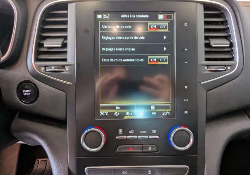 Vue rapprochée de la console centrale de la Renault Mégane IV avec écran tactile affichant les aides à la conduite.