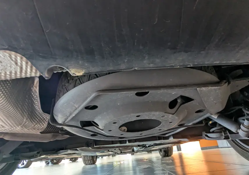 Vue en contre-plongée sous la Renault Mégane IV gris, montrant la roue de secours et le châssis arrière.