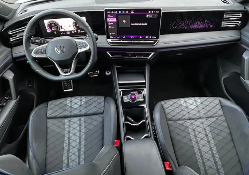 Vue intérieure avant du Volkswagen Tiguan R-Line 2024 avec tableau de bord numérique et sellerie tissu ArtVelours gris à motifs géométriques.