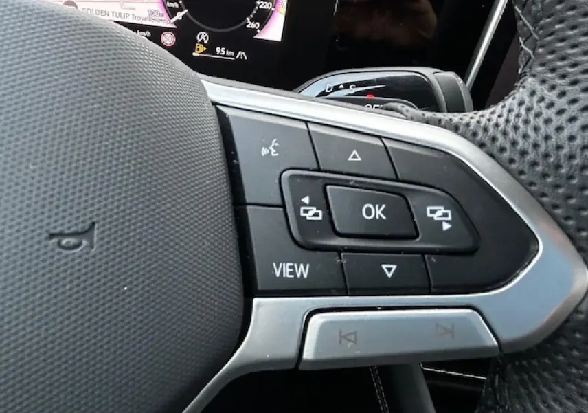 Gros plan sur les commandes multifonctions côté gauche du volant perforé du Volkswagen Tiguan gris clair 2024.