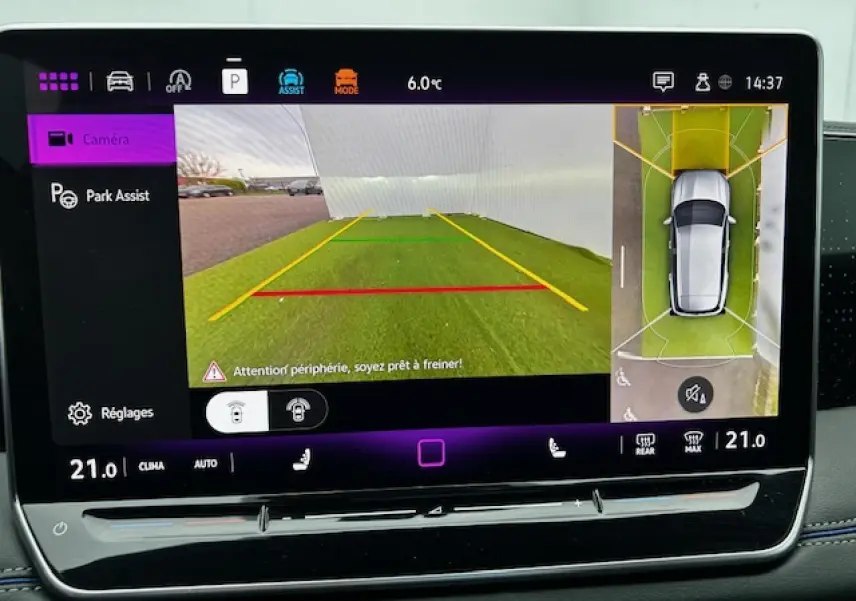 Écran tactile du Volkswagen Tiguan 2024 montrant la caméra de recul et l'assistance au stationnement avec vue aérienne du véhicule gris clair.