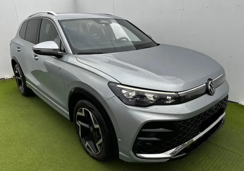 Volkswagen Tiguan III gris clair en 3/4 avant droit avec jantes noires et détails chromés sur calandre et pare-chocs.