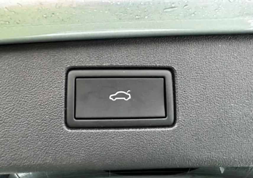 Bouton noir de déverrouillage du coffre sur la console intérieure du Volkswagen Tiguan gris clair 2024.