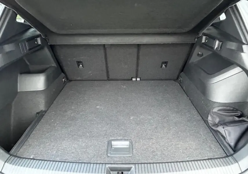 Coffre ouvert du Volkswagen Tiguan III gris clair, vue intérieure arrière montrant un espace de chargement spacieux.