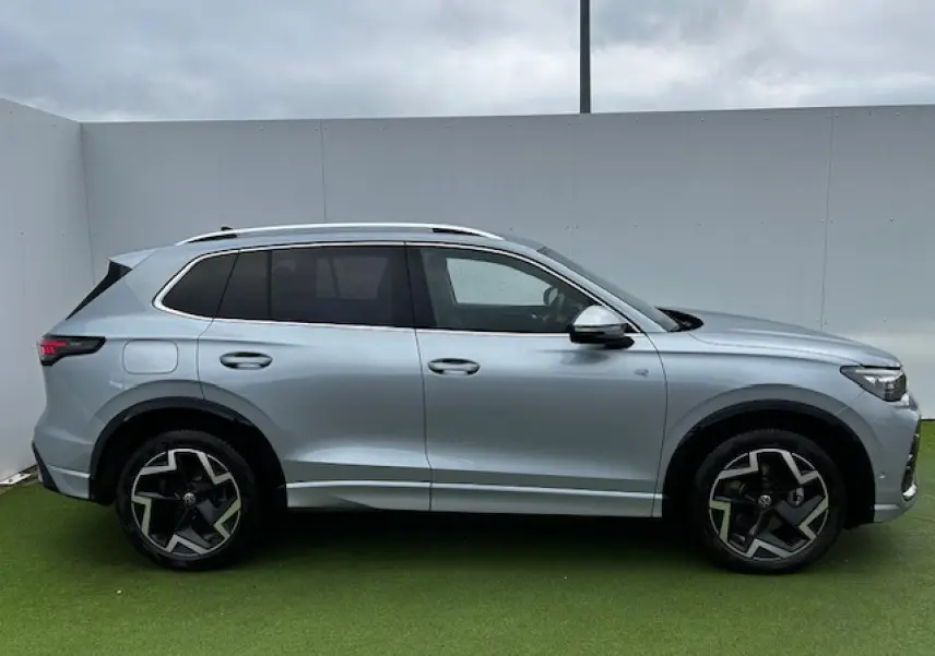 Volkswagen Tiguan III gris clair vu de profil côté gauche avec jantes alliage 19 pouces et vitres teintées.