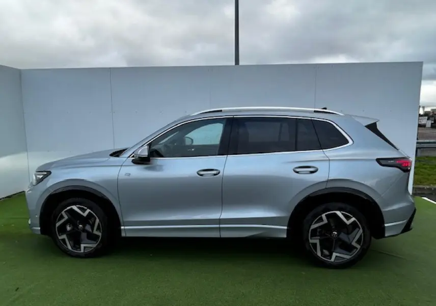 Profil côté gauche du Volkswagen Tiguan III gris clair 2024 avec jantes alliage noires et détails R-Line visibles