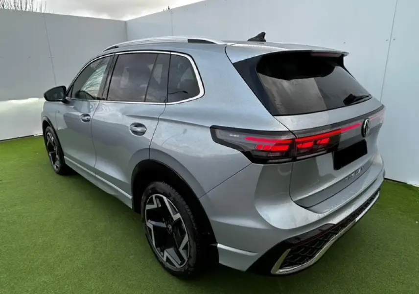 Vue 3/4 arrière droite d'un Volkswagen Tiguan gris clair avec feux arrière LED et jantes noires distinctives.