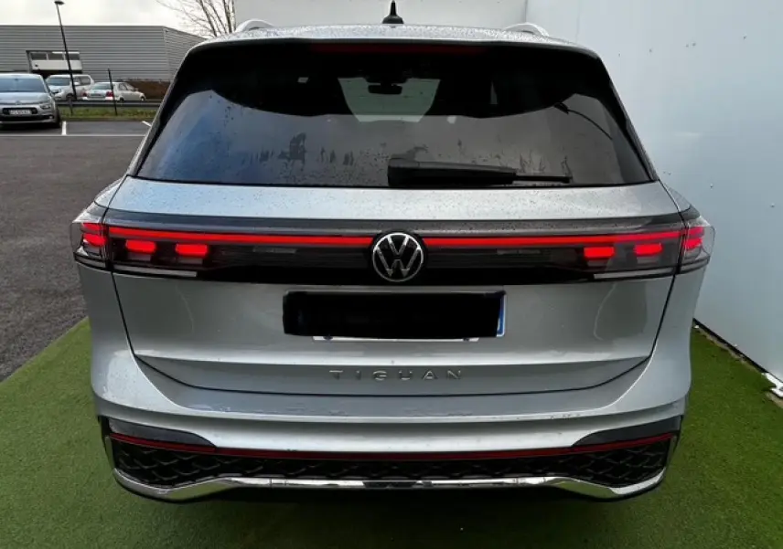 Vue arrière d'un Volkswagen Tiguan gris clair 2024 avec feux arrière LED reliés par une bande lumineuse rouge.