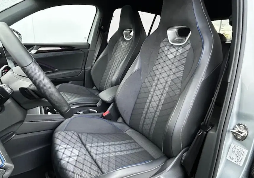 Vue intérieure côté conducteur du Volkswagen Tiguan gris clair 2024 avec sièges sport en tissu ArtVelours à surpiqûres bleues.