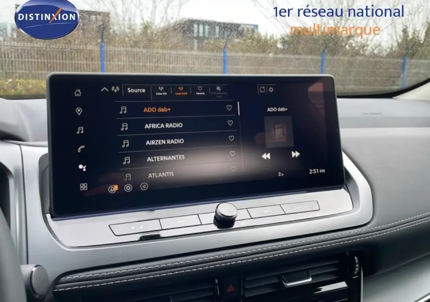 Écran tactile central du Nissan Qashqai 2026 affichant les stations radio, intérieur gris avec finitions modernes.