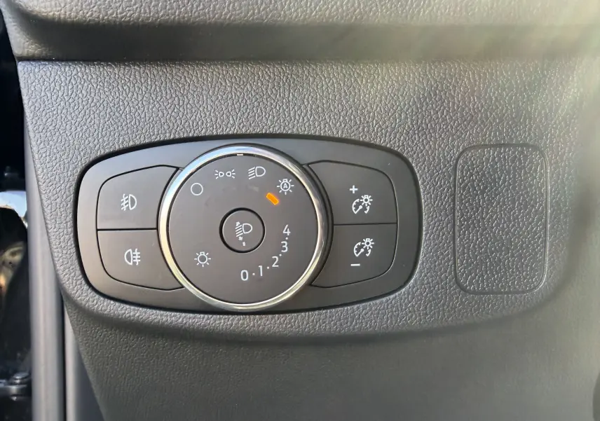 Gros plan sur la molette de réglage des phares et des feux antibrouillard dans l’habitacle noir du Ford Focus IV ST-Line X.