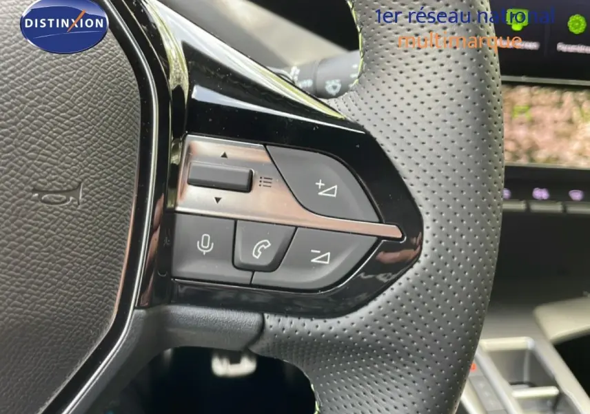 Gros plan sur les commandes au volant en cuir perforé de la Peugeot 308 gris Artense, version hybride 2026.