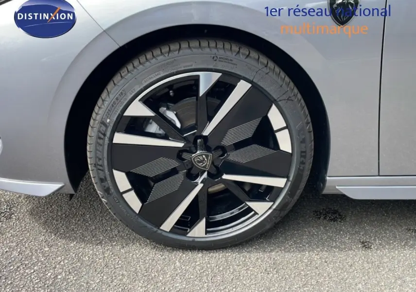 Gros plan sur la roue avant droite d’une Peugeot 308 gris Artense métal, avec jante noire et argentée au design moderne.