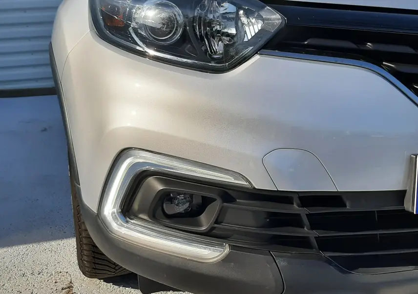 Gros plan sur l'avant gauche du Renault Captur gris platine, mettant en valeur son phare et antibrouillard LED.