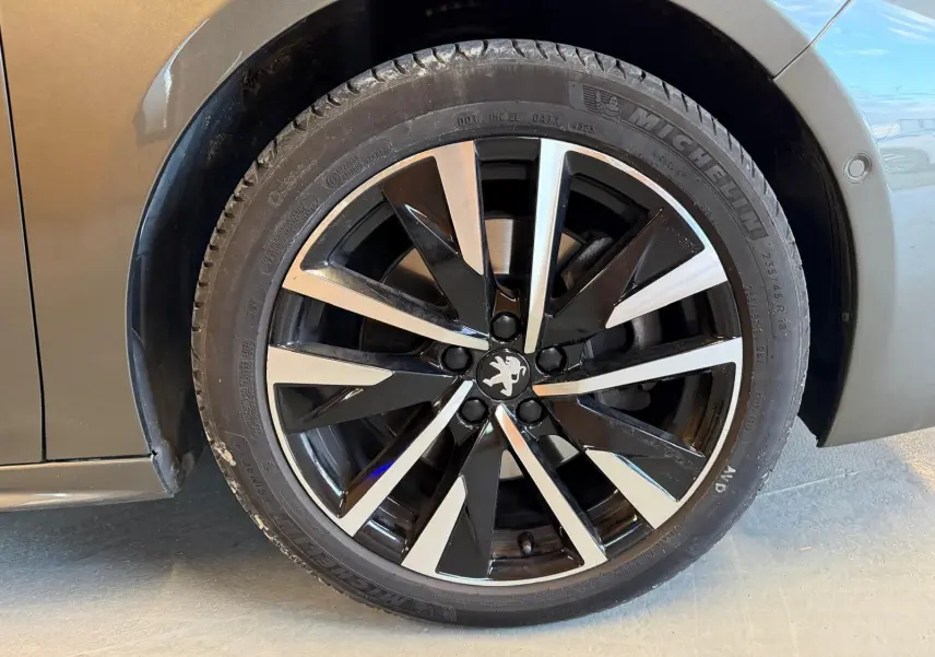 Gros plan sur la jante alu noire et argentée d'une Peugeot 508 gris, avec logo lion au centre.