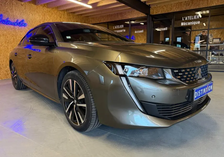 Peugeot 508 gris métallisé vue 3/4 avant droit avec jantes alliage et calandre chromée en intérieur showroom.