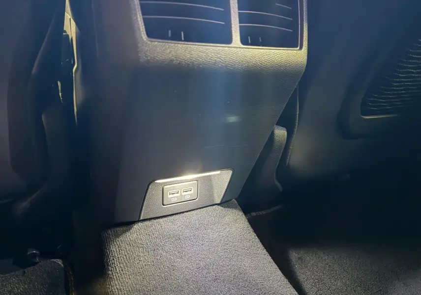 Prise USB double arrière sur console centrale noire dans Peugeot 508 gris, vue rapprochée du bas intérieur.