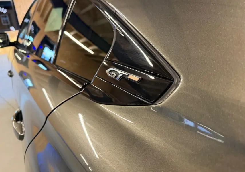 Détail du logo GT sur la custode côté droit d’une Peugeot 508 gris métallisé en intérieur.