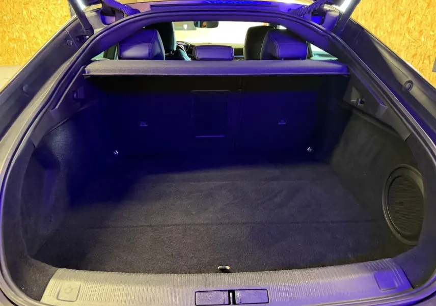 Vue intérieure du coffre ouvert de la Peugeot 508 gris, montrant un espace de rangement propre et un haut-parleur latéral.