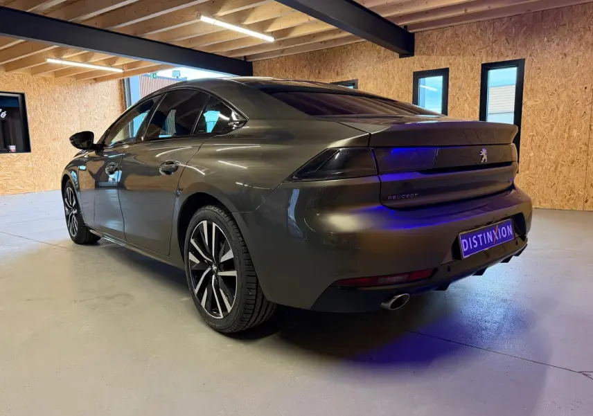 Vue 3/4 arrière droite d'une Peugeot 508 gris métallisé avec jantes alu et feux arrière à LED dans un garage.