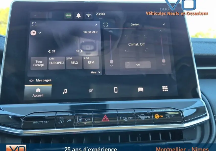Écran tactile central du Jeep Compass 2024 gris montrant les réglages radio et climatisation, avec boutons de commande en dessous.