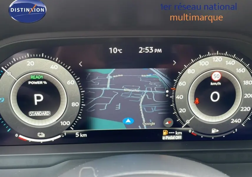 Vue rapprochée du tableau de bord numérique du Nissan Qashqai gris, affichant la navigation et les compteurs digitaux.