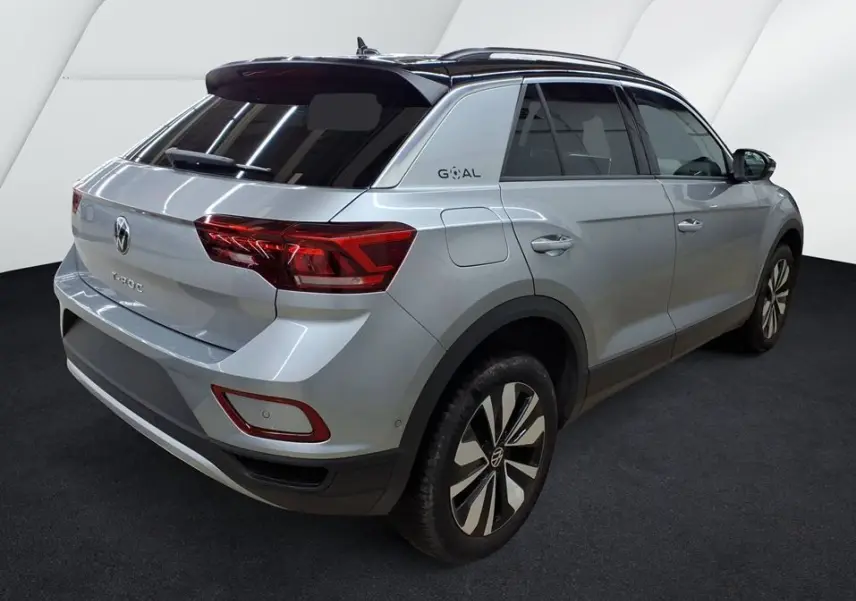 Volkswagen T-Roc gris clair en 3/4 arrière droit, avec toit noir et jantes alliage distinctives.