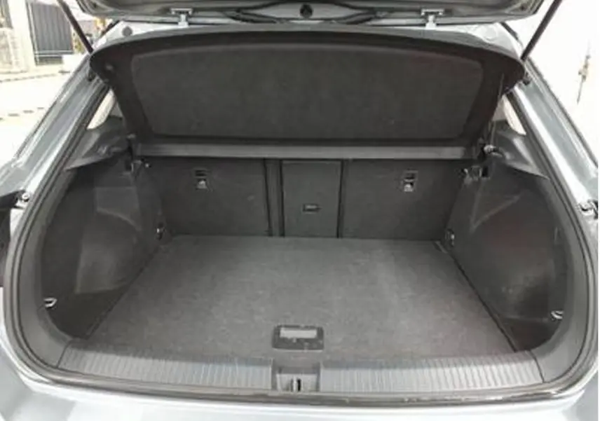 Coffre ouvert vu de l'arrière d'un Volkswagen T-Roc gris clair 2025, espace de chargement vide et propre.