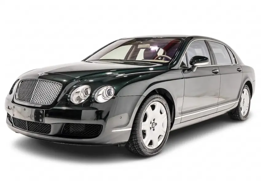 Vue 3/4 avant droite d'une Bentley Continental Flying Spur vert foncé avec calandre chromée et jantes blanches.