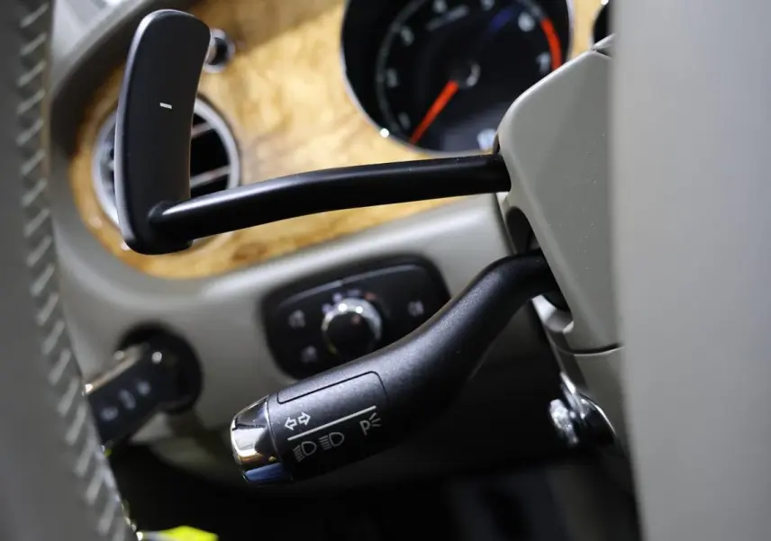Gros plan sur la commande de clignotant et phare dans l’habitacle beige d’une Bentley Continental Flying Spur 2006.