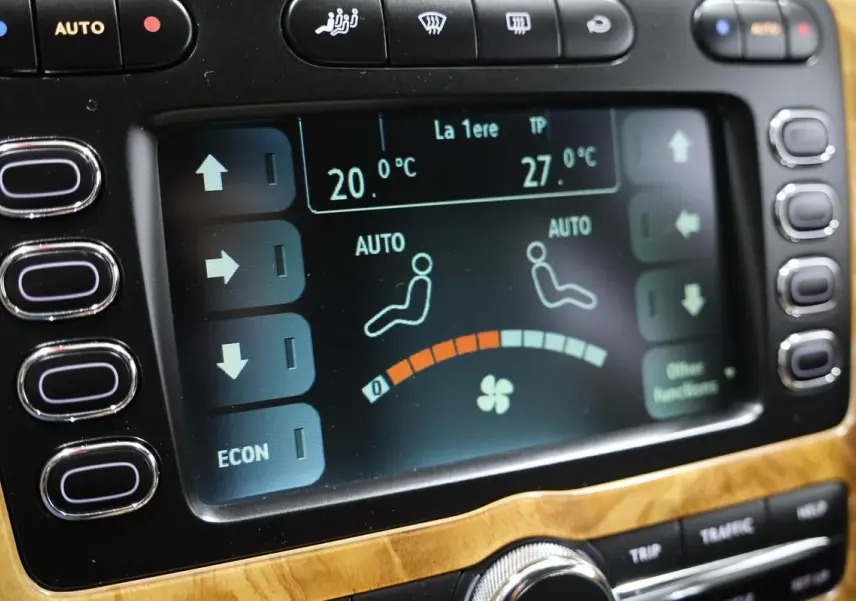Écran tactile de la climatisation automatique sur tableau de bord en bois clair d’une Bentley Continental Flying Spur.