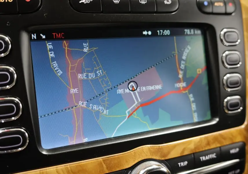 Écran GPS central de la Bentley Continental Flying Spur 2006 avec contour en bois clair et boutons noirs latéraux.